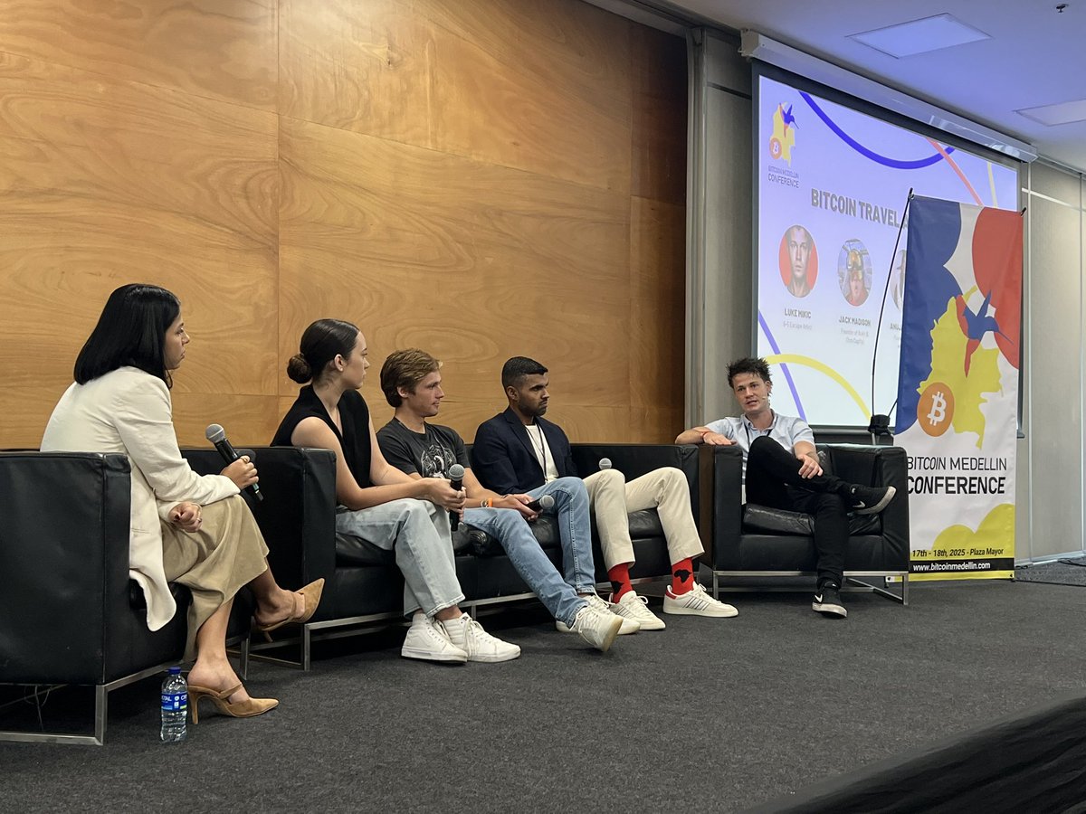 Santosh on a panel at Bitcoin Medellín Conference 2025, seated with four other panelists in front of a Bitcoin Travel discussion screen