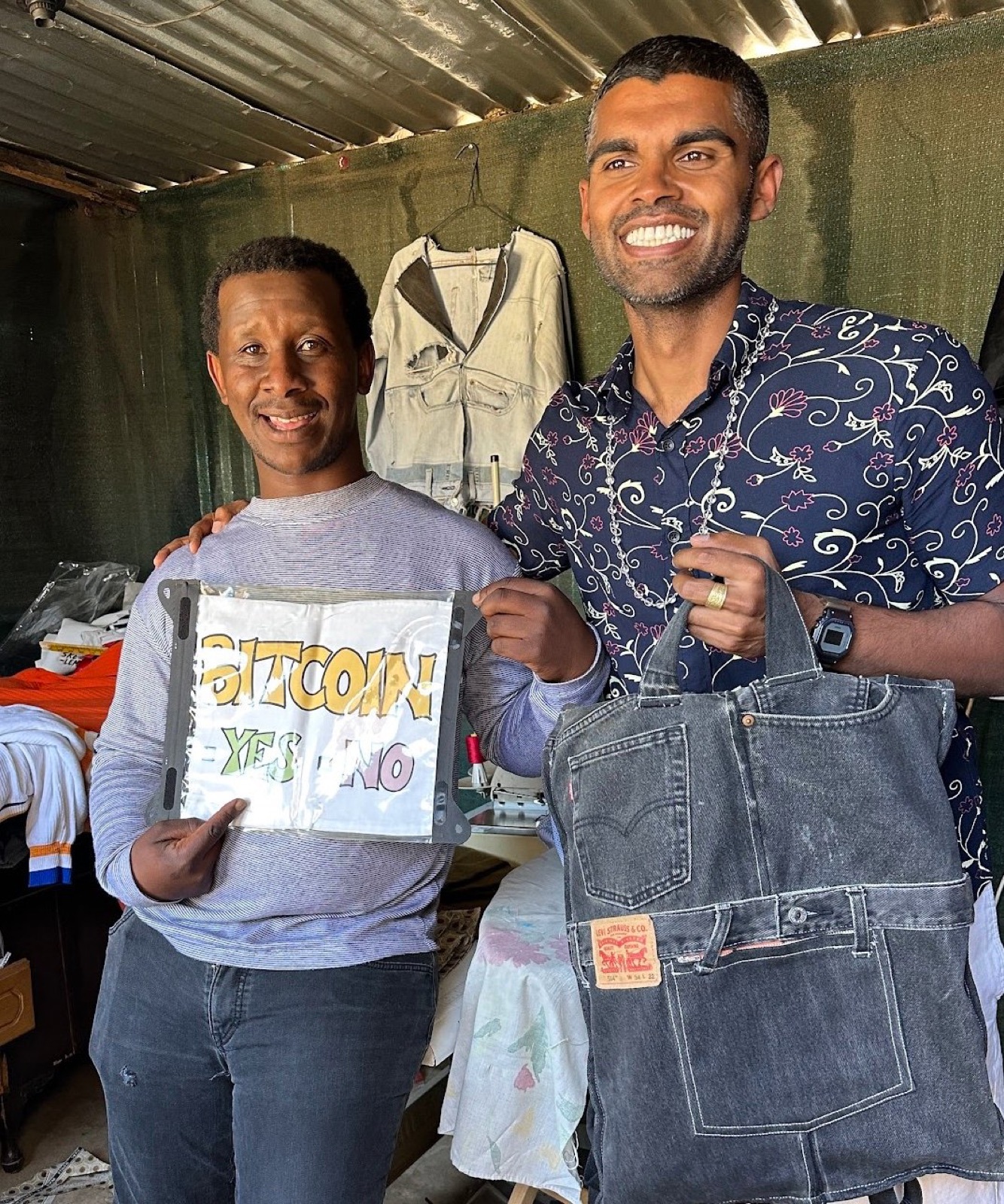 The apparel designer's shop, holding the Bitcoin sign alongside a tote bag made from recycled denim